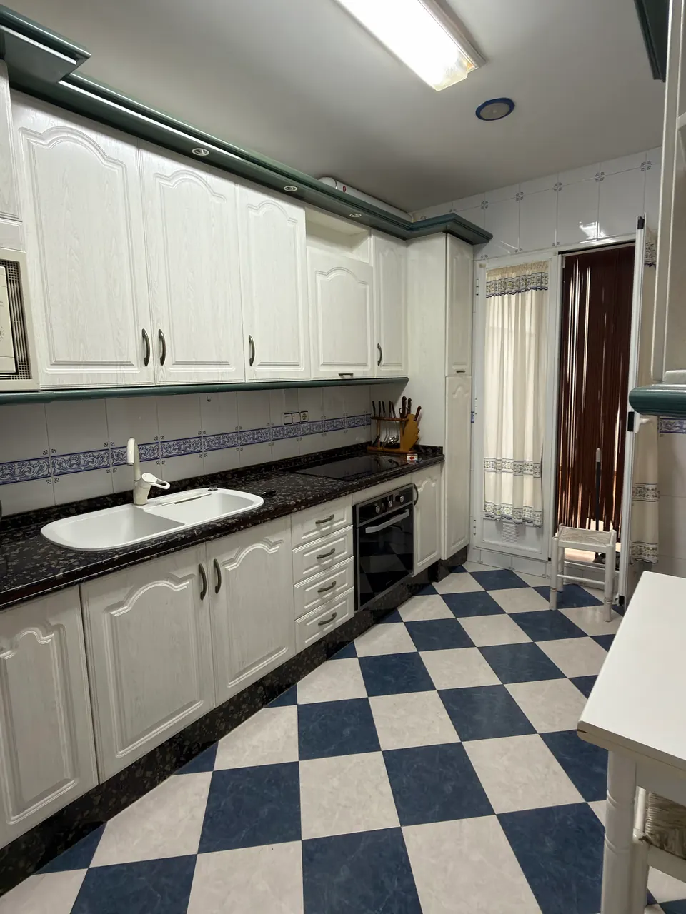 Cocina de muebles blancos con horno y vitrocerámica